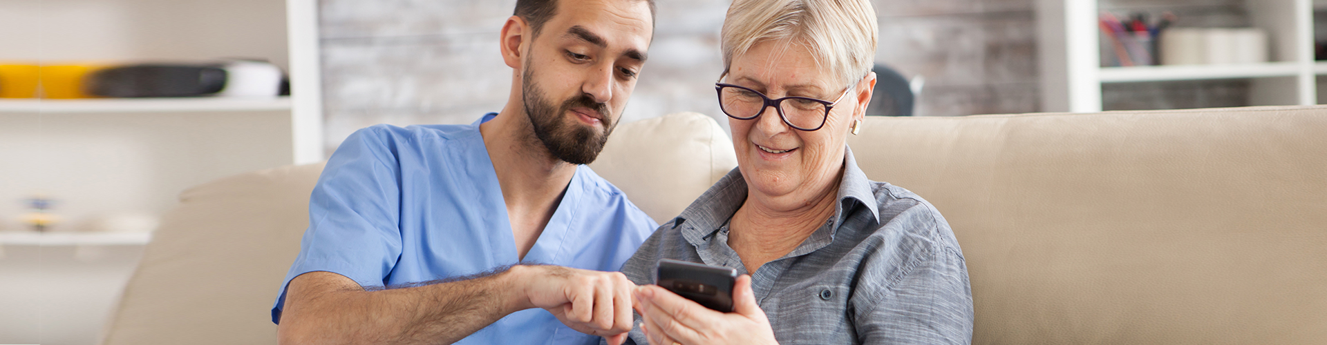 caretaker helps elder woman on phone